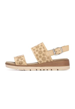 Sandalias de cuero beige con diseño floral perforado, correa ajustable en el tobillo, base con textura de madera y suela ligera de goma con muescas.