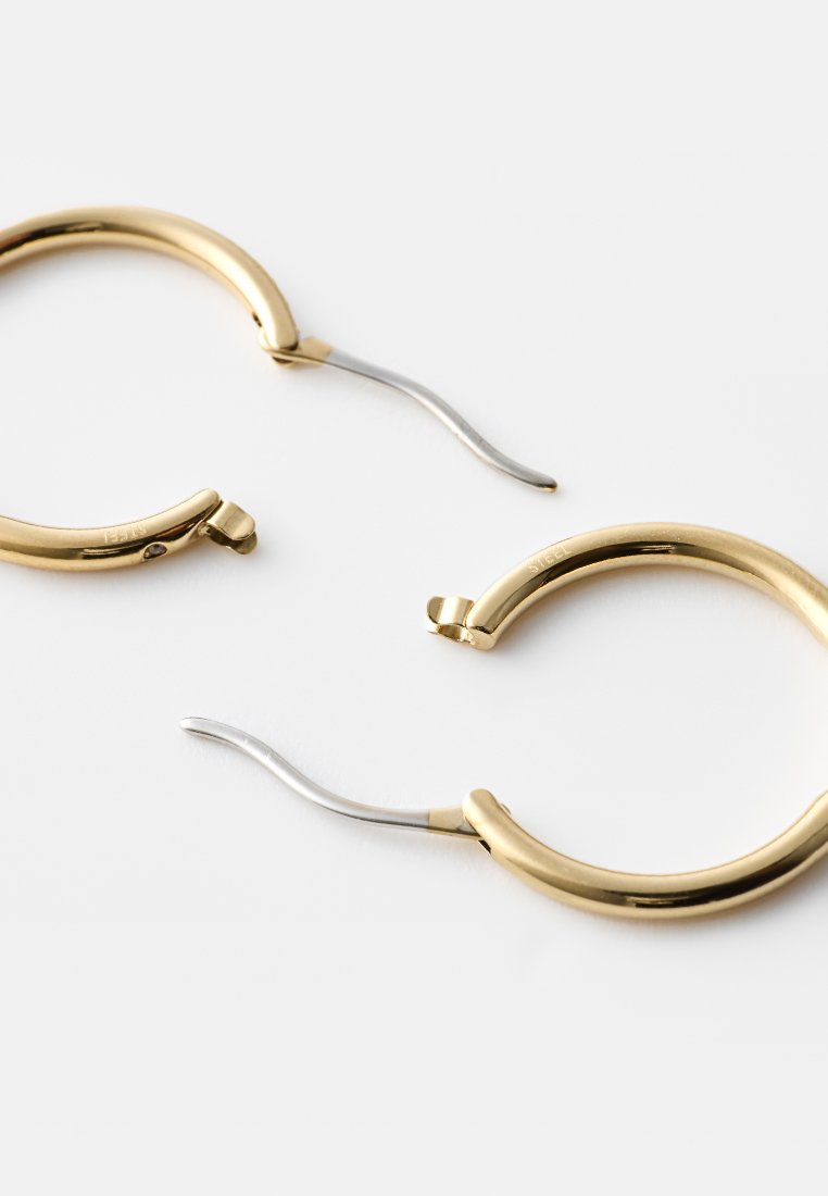 Goldfarbene Creolen mit glatter Oberfläche und schlankem Design. Ein Ohrring verfügt über ein silberfarbenes Scharnier für einen sicheren Verschluss.