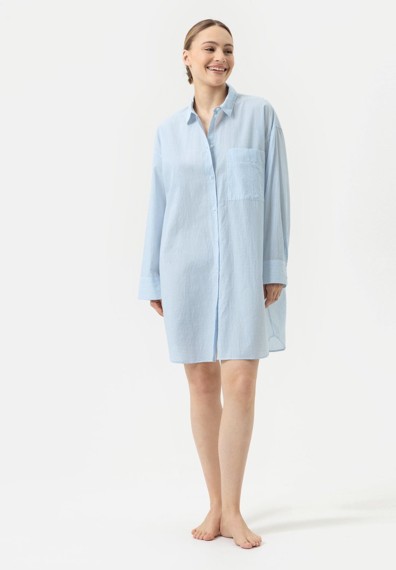 Chemise boutonnée à manches longues bleu clair avec une poche, présentant des rayures verticales et une coupe décontractée, atteignant la longueur mi-cuisse.