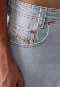 Helle blaue Jeans aus Denim mit kupferfarbenen Metallbeschlägen, auffälligen Nähten, einem Fronttaschenetikett und einem klassischen Fünf-Taschen-Design.