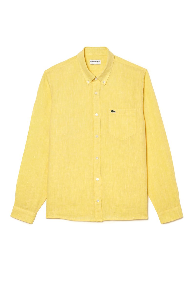 Camisa amarilla de manga larga con botones hecha de una tela texturizada. Presenta un único bolsillo en el pecho y un pequeño logo de Lacoste en el lado izquierdo.