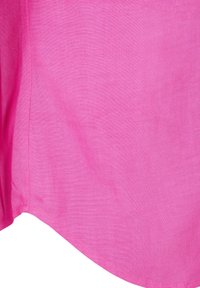 Svijetlopinkasta tkanina s vidljivom teksturom, s šavom koji ide vertikalno i zakrivljenom donjom ivicom.