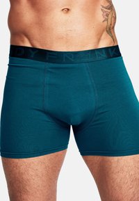 Turkosa kalsonger för män med svart midjeband som har det prägling av varumärket. Mjuk, elastisk tyg med en åtsittande passform, synlig sömsdetalj.