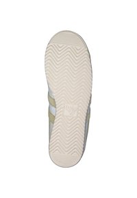White sneaker with suede yellow accents, textured rubber sole featuring a zigzag pattern, and a logo on the heel.