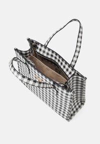 Svart- och vitrutig tygkasse med två handtag, dragkedja upptill och innervarierade fack. Mjuk yta med detaljer i guldfärg.