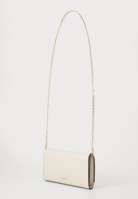 Borsetta in pelle crema con tracolla in catena dorata, forma rettangolare, superficie liscia, caratterizzata da un design minimalista e dettagli con logo.
