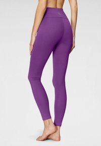 Leggings high-waisted di colore viola realizzati in un tessuto liscio e elasticizzato, con un design aderente e senza motivi o hardware visibili.