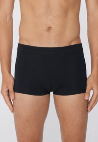 Caleçons boxers noirs en tissu lisse, avec une large ceinture élastique et des détails de couture, conçus pour un ajustement snug.