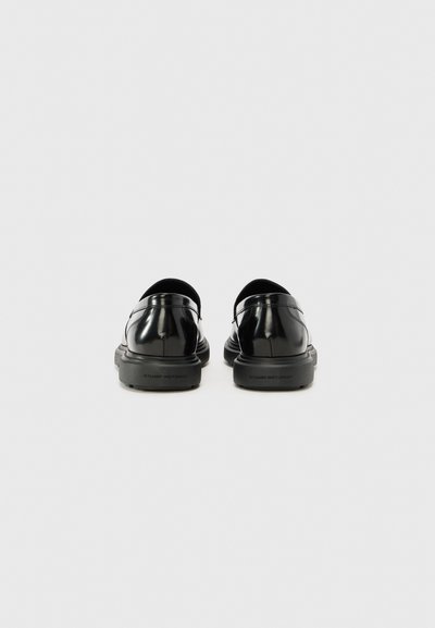 Pantofi slip-on din piele neagră cu un finisaj neted și lucios, vârf rotunjit și talpă din cauciuc texturat. Prezintă accente minime de cusătură.