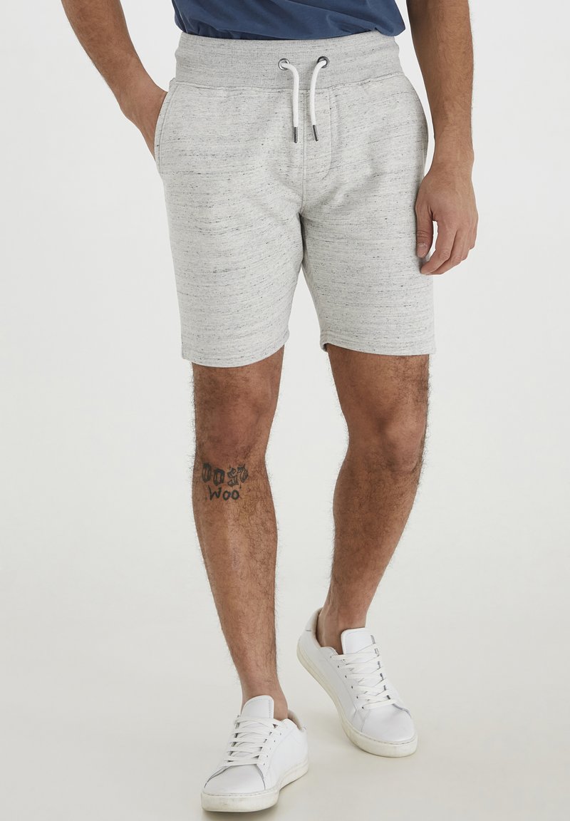 Grå bomullsshorts med snor i livet, sidelommer og subtil flekkete tekstur. Kombinert med hvite joggesko.
