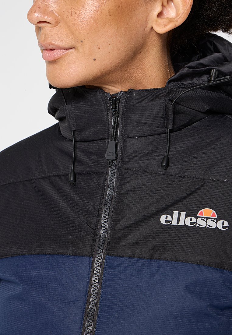 Giacca zip-up nera e blu con cappuccio. Presenta un tessuto testurizzato, cordini elasticizzati e un piccolo logo sul petto.