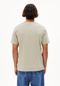 Hellgraues Baumwoll-T-Shirt mit Rundhalsausschnitt und kurzen Ärmeln, mit einem entspannten Schnitt, glatter Textur und einem kleinen Seitenlabel.