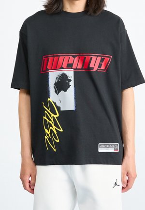 Black cotton t-shirt featuring a prominent red "twenty" graphic, a silhouette print, yellow script, and a logo patch, relaxed fit design.