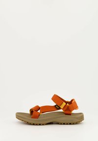 Sanda n con correa naranja que cuenta con una webbing ajustable, una suela acolchada en tono marrón y una suela exterior de goma texturizada para mayor tracción.