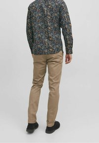 Pitkähihainen, laivastonsininen kukkapaita, jossa napitusetu, yhdistetty vaaleanruskeisiin istuviin housuihin ja mustiin kenkiin. Teksturoitu kangas vaihtelevin värikorostein.