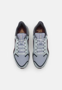Chaussures de course bleu clair avec des accents gris foncé. Tige en mesh, fermeture à lacets, embout texturé et détail du logo sur la languette.