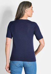 Dunkelblaues Kurzarmoberteil in taillierter Form, aus glattem Strickstoff gefertigt. Mit Rundhalsausschnitt und geripptem Saum.
