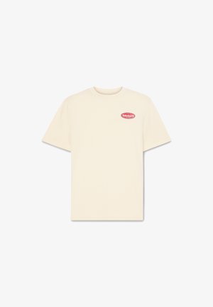 Béžové bavlněné tričko s krátkými rukávy, kulatým výstřihem a malou červenou nášivkou s logem na levé straně hrudi.