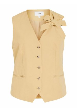 Gilet sans manches beige pour femmes avec col en V, boutons sur le devant, deux petites poches avant et un grand nœud en tissu sur l'épaule gauche.