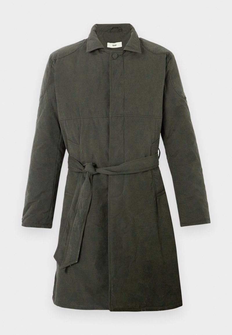 Donkergroene, knielange jas van gestructureerde stof. Heeft een ceintuur in de taille, knoopsluiting en zijzakken. Eenvoudig kraagontwerp.