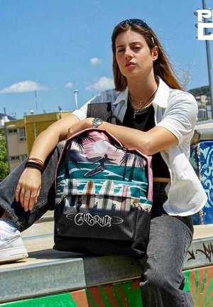Mochila negra y rosa con un diseño costero que presenta tablas de surf y palmeras. El material parece ser de tela, con correas ajustables.