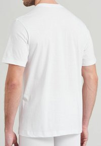 Witte katoenen t-shirt met korte mouwen, ronde hals en een gladde textuur. Achteraan is er een ontspannen pasvorm te zien met minimale stikdetails.