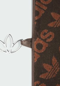 Brauner Stoff mit einem sich wiederholenden Logo-Muster in Rostfarbe; verfügt über einen silbernen Metalldetail mit Logo und einen braunen Bandakzent.