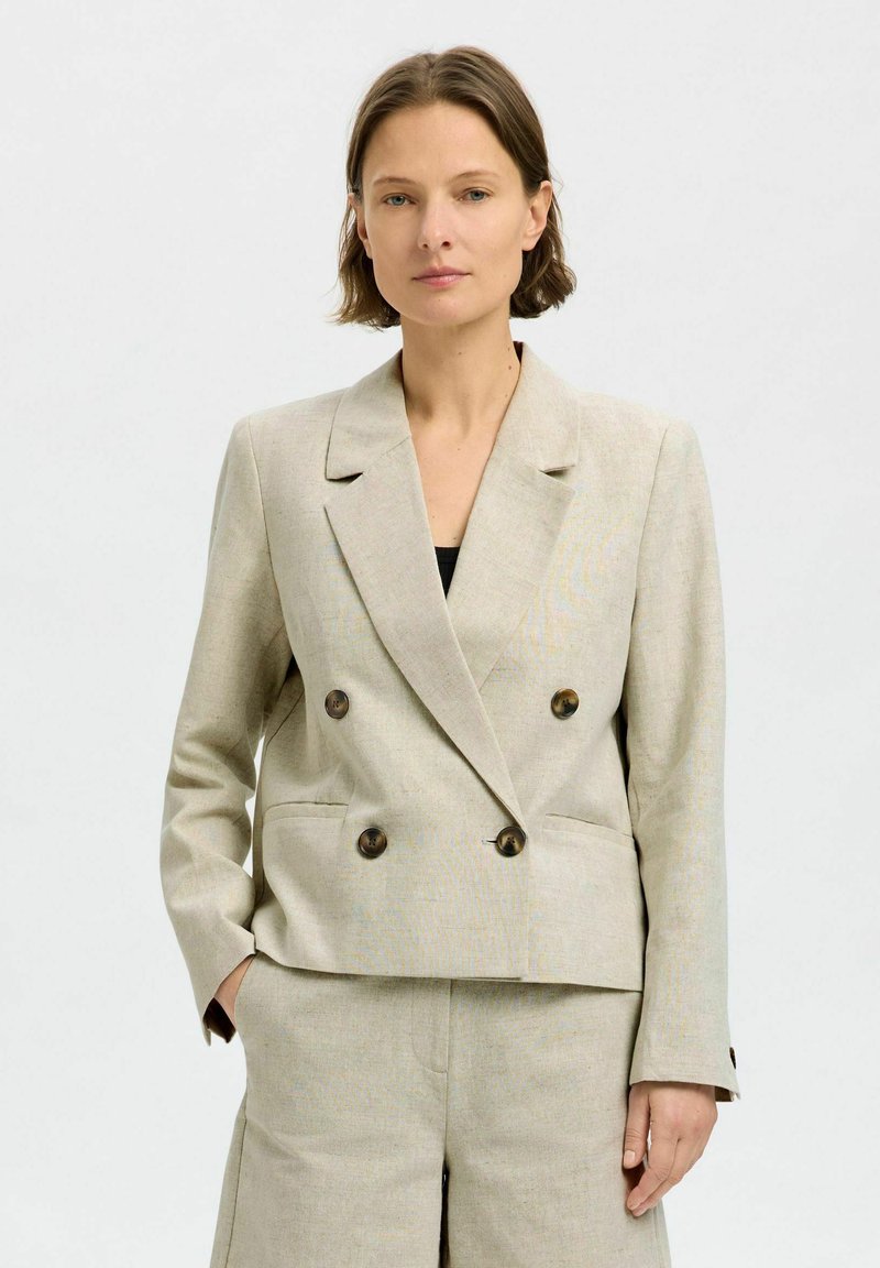 Beige linned dobbeltrækket blazer med notched lapels, to forlommer og brune knapper. Glat tekstur og skræddersyet pasform.