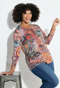 Top de manga larga colorido que presenta un patrón abstracto vibrante con remolinos y motivos en rojo, azul y naranja sobre una tela ligera.