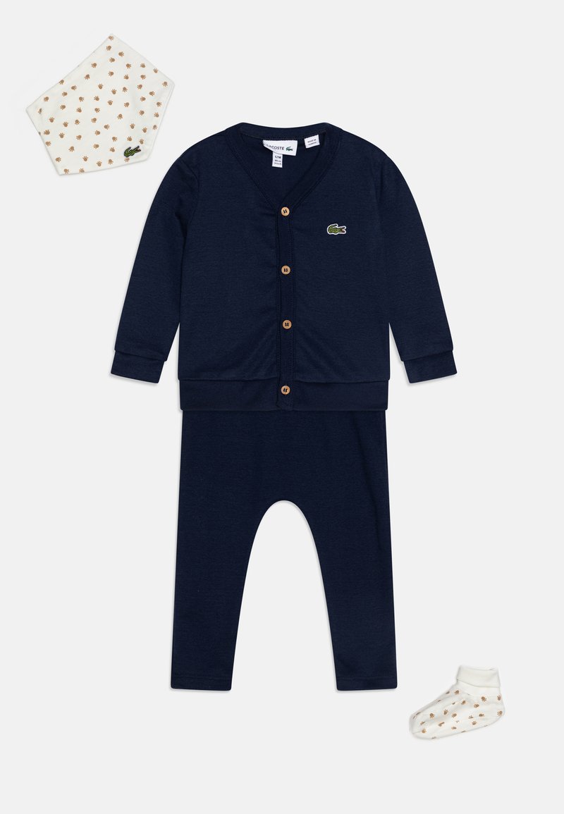 Navy cotton infant set featuring a long-sleeve cardigan with wooden buttons, matching pants, a patterned bib, and a sock with gold accents.