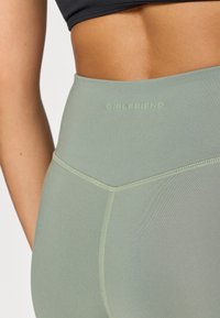 Leggings de cintura alta, en un verde claro, con una textura suave y un branding sutil, que cuentan con una cinturilla cosida y un diseño sin costuras y aerodinámico.