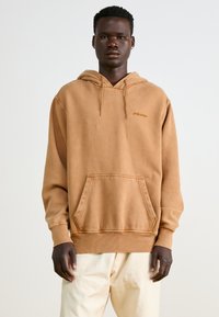 Brown cotton hoodie with a front pocket, adjustable drawstring hood, ribbed cuffs, and embroidered logo on the chest. Smooth texture.