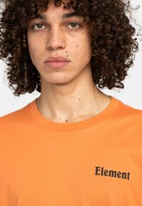 Oranžové bavlněné tričko s kulatým výstřihem a krátkými rukávy, na levé straně hrudi s černým logem "Element".