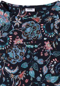 Tissu bleu marine avec des motifs floraux et de feuilles multicolores en bleu, rose et marron, doté d'un col rond et d'une étiquette de marque CECIL.