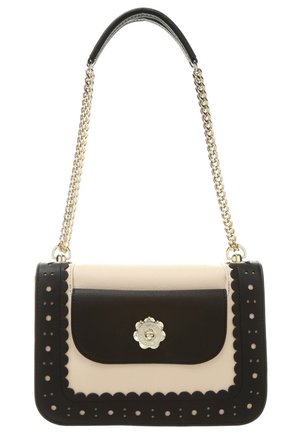 Small rectangular beige handbag with black scalloped edges, front pocket with floral silver clasp, and gold chain strap with black leather top.