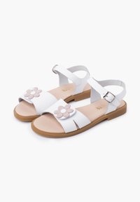 White leather sandals featuring a flower design on the strap, open-toe style, adjustable ankle buckle, and a light brown rubber sole.