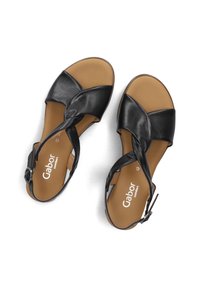 Zwarte leren sandalen met kruislings banden, een gewatteerde bruine zool en een verstelbare gesp aan de zijkant. Gabor comfort merkvermelding zichtbaar.