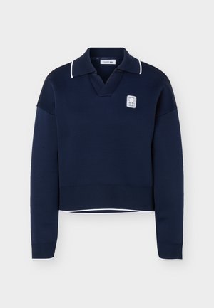 Suéter azul marino de manga larga con ribete blanco en el cuello y los puños, con un pequeño parche de logo blanco en el pecho izquierdo.