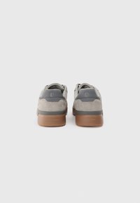 Zapatos de ante gris y sintético con suela de goma marrón. Presentan un diseño suave, bordes redondeados y un logo en el talón.