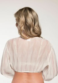 Weißes, durchscheinendes Blusenkleid mit einem strukturierten, zerknitterten Stoff. Verfügt über weite, gepuffte Ärmel und eine geraffte Taille auf der Rückseite.