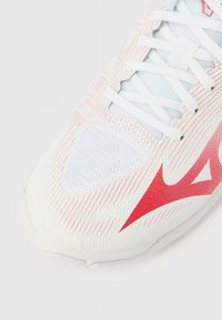 Λευκό και γαλάζιο αθλητικό παπούτσι με υφασμάτινο επάνω �μέρος, κόκκινες λεπτομέρειες και λευκά κορδόνια· μυτερή μύτη και λεπτές ριγέ σχεδιάσεις.