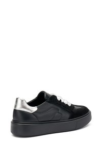 Baskets en cuir noir avec un revêtement en suede noir texturé, accent métallique argenté au talon, et lacets blancs sur une épaisse semelle noire.