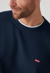 Donkerblauwe sweatshirt van een gladde katoenmix stof, met een ronde hals en een rood Levi's logo-label dat op de voorkant is gestikt.