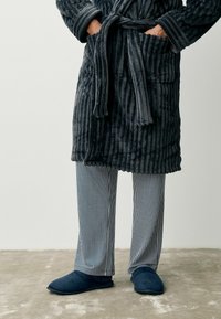Charcoal gray striped robe with textured fabric, paired with blue striped pajama pants and dark blue slippers, displayed on a neutral background.