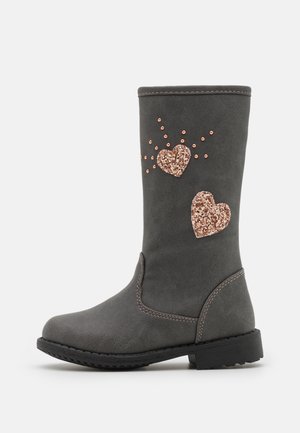 Botte gris foncé mi-mollet avec semelle noire, décorée de deux cœurs scintillants en or rose et de petits clous ronds sur le côté extérieur.