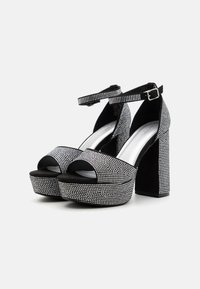 Černé platformové sandály se zdobením z rhinestones, otevřenou špičkou, řemínkem kolem kotníku a masivním podpatkem se hladkým stříbrným stélkou.