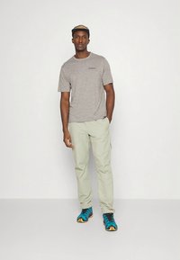 Grå lyng-t-skjorte, lysegrønne bukser og joggesko med blå detaljer. Avslappet, ledig passform med kortermet design.