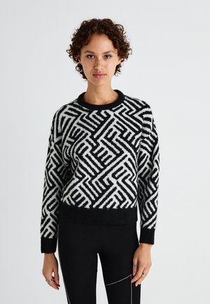 Pull noir et blanc avec des motifs géométriques, col rond et poignets côtelés. Matériau tricoté chaud et texturé.