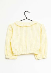 Blusa gialla corta con design a scacchi, maniche a palloncino e colletto arrotondato. Tessuto leggero e texture con elastico ai polsini e all'orlo.