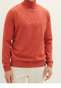 Rode coltrui van fijn gebreide stof met ribbelgeknoopte manchetten en zoom. Vlotte textuur, aansluitend ontwerp, geschikt voor layering of casual draagstijl.